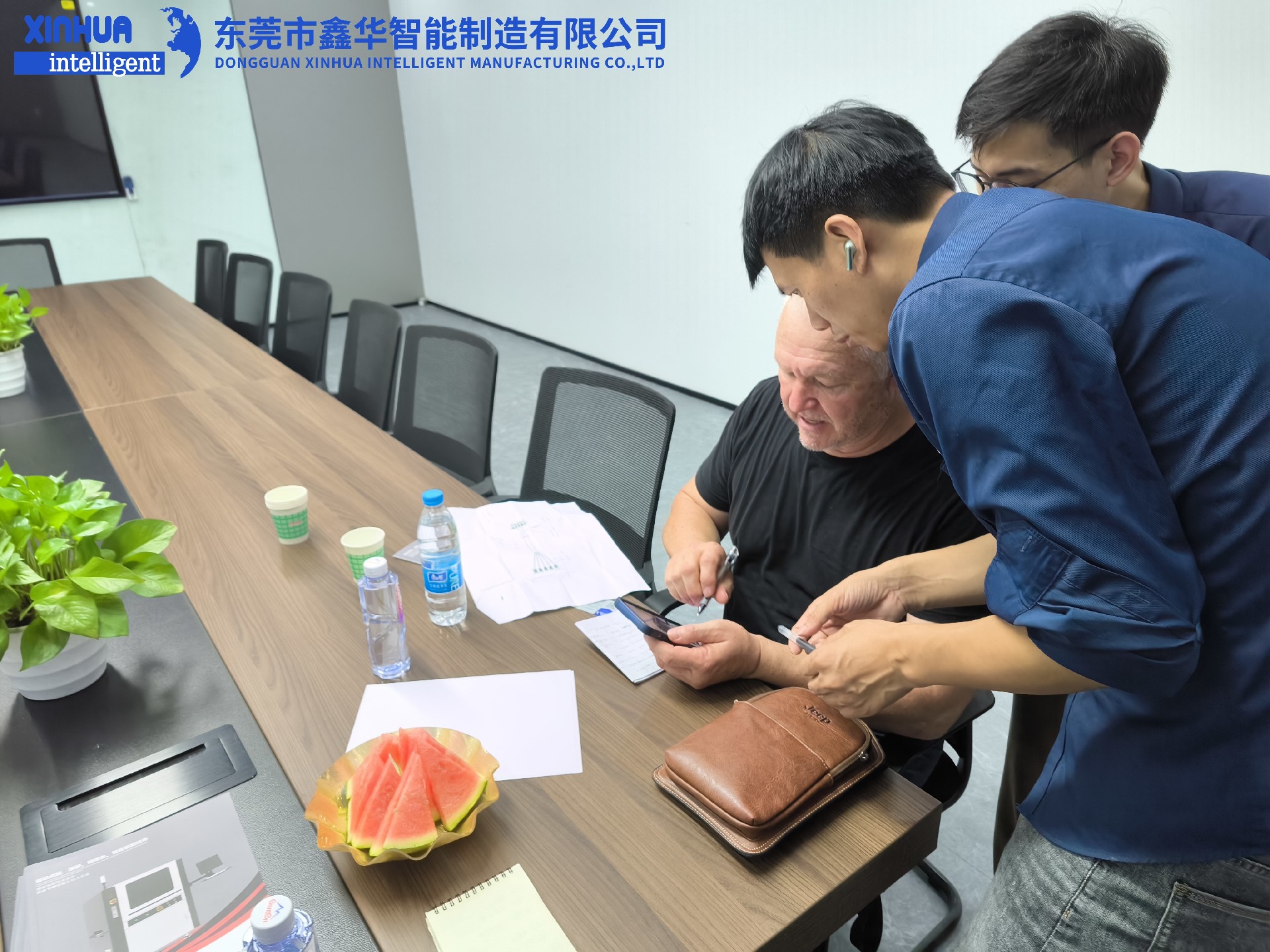 業務部2位男同事在給美國客戶耐心介紹自動鎖螺絲機性能